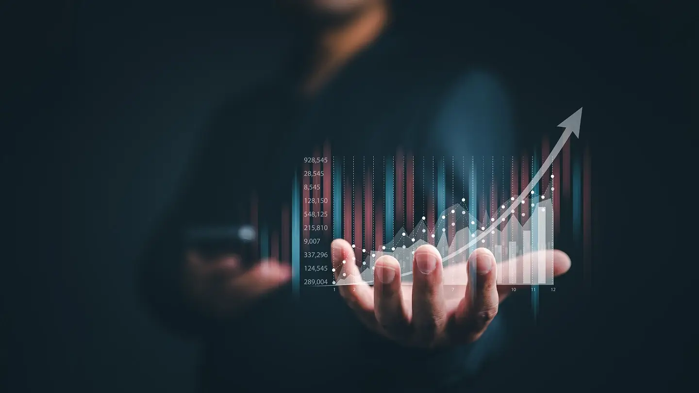 Persona sosteniendo una proyección digital de datos financieros con gráficos ascendentes y una flecha que simboliza crecimien