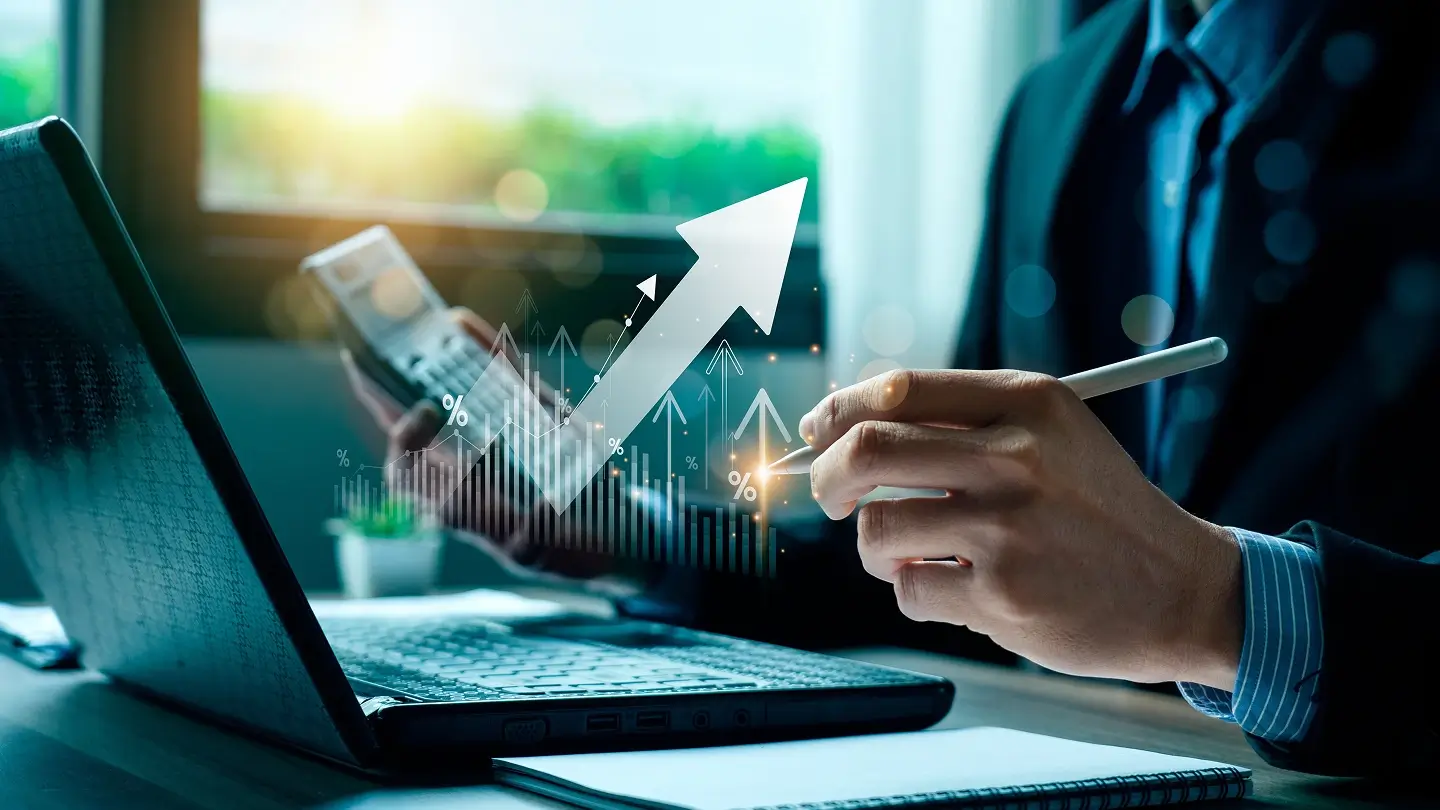 Persona trabajando con laptop y calculadora, analizando crecimiento financiero